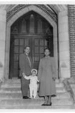 An unidentified Gammon Student and family stand on campus steps.