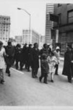 Joseph E. Lowery is shown with others (including Hosea Williams, second from right) leading a crowd of protesters down a street.