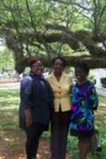 Two Spelman SIS students stand with Darlene Clark unde a large live oak tree.