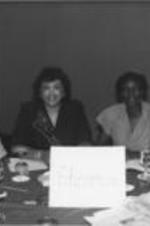 A group of women are shown at a table with an "Education" sign at a national AIDS and Black Community conference.