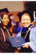 View of Beverly Tatum handing diploma to graduate and posing for photograph.