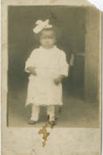 A child in a light colored outfit stands in a doorway. Written on verso: April 5, 1926; OR Penn $5.00.