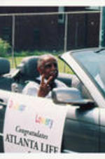 Joseph E. Lowery flashes a peace sign as he rides in a parade.