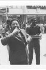 Hosea Williams speaks into a microphone at the Sanitation Worker's Strike in Atlanta. Written on accompanying document: Hosea Williams speaking during march of sanitation strikers.