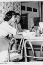 A man and a woman sit at an otherwise empty lunch counter.