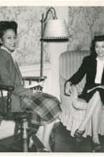 Interior of a dormitory lounge at Atlanta University with two seated students. Written on verso: Students relax at Atlanta University Dormitory - 1945