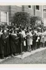 Men and women wearing choir robes, perform at commencement.
