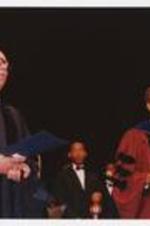 Colin Powell is on stage with other men at the summer commencement. Written on verso: CAU Summer Commencement - incl. Colin Powell, Photo by Jim Alexander.