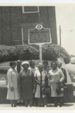 Outdoor group portrait of men and women stand in front of the historic site sign at Bethel AME Church.