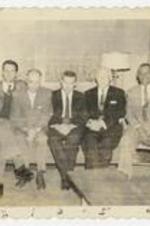 Indoor group portrait of six men seated on a sofa. Written on verso: Devil's Lake, S.D. Oct. 1, 1957, Team of workers from the Interboard Commission are the following: 1. LeRoy Walker - Evangelism, 2. Randle Dew - Education, 3. Arthur Moore - Missions, 4. J. Herbert Touchstone - Stewardship, 5. Bishop E.E. Voight, 6. Huff - Dist Supt.