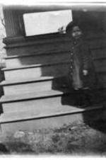 A child stands on the stairs of a home.