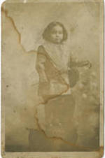 A child stands on a chair holding a small cane.