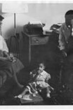 An unidentified Gammon student and family seated in a living room.