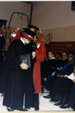 An unidentified man receives a red hood as he crosses the stage.