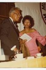 View of a man and woman speaking. Written on verso: "Dr. Robert Threatt and Mrs. Helen Threatt at Man of the Year Awards Ceremony".