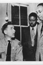 Martin Luther King, Jr. stands with Ralph D. Abernathy as they speak with a Montgomery, Alabama police officer.