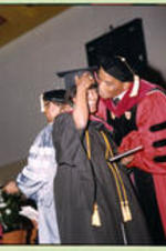 An unidentified faculty member kisses a graduate to congratulate her on graduating.