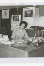 Ellen Magby sits at a desk in an office.