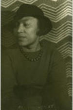 Portrait of Zora Hurston sitting in front of a patterned background.