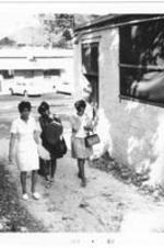 Three women walk through an alley carrying books.