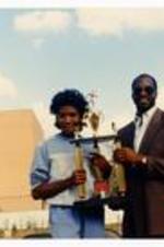 Photograph of student athlete and Edwin Moses. Written on verso: Edwin Moses Homecoming Oct. 27, 1984.