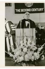 An unidentified man delivers a speech at a podium.