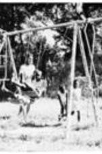 Unidentified children play outside on a swing set.
