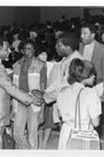 Southern Christian Leadership Conference President Joseph E. Lowery shakes hands with an unidentified man in an auditorium during a Martin Luther King, Jr. memorial observance event at Clark College.
