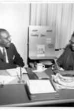 Rober E. Penn and an unidentified woman work in an office at the First Baptist Church of Gary. Written on verso: "Me &amp; my boss"