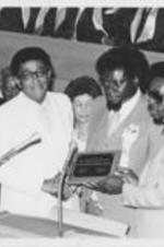 Joseph E. Lowery and E. Randel T. Osburn are shown presenting Reverend Bennie Robert Rountree with an award in front of Evelyn G. Lowery and others.