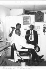 Three men laugh together in a barbershop. Written on recto: Brown "Barber."