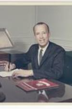 Hugh M. Gloster sits at his desk.