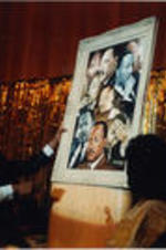 An unidentified individual is shown holding up a Martin Luther King, Jr. portrait for display.