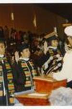 View of graduates on stage. Written on verso: 1990 Commencement (platform). Captain Gordon E. Fisher, Professor of Naval Science, Morehouse College.