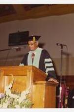 View of a man at podium in graduation cap and gown.