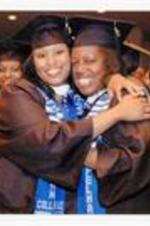 View of two graduates embracing at commencement.