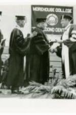 President Hugh Gloster on stage during Commencement with Dr. Lee, Dr. Franklin Forbes, and Rev. Martin Luther King Sr.. Written on verso: Commencement 1969 Lee, Forbes, King Sr. and Gloster.