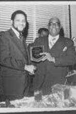 Dr. William Whatley receives the Turner Theological Seminary Outstanding Alumni Award from a man inside the ITC dining hall.