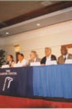 Jimmy Carter is shown speaking at a The Carter Center event alongside panelists including Joseph E. Lowery and Evander Holyfield, who were members of an election observation team for the Jamaican elections.