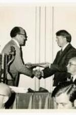 President Hugh Gloster with Jimmy Carter and unidentified persons. Written on verso: President Hugh Gloster presents Award to Govenor Jimmy Carter at Higher Education Award Banquet: May 9, 1972.