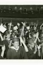 View of group of graduates cheering at commencement.