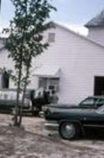 A hearse parked outside of an unidentified church at a funeral. Unknown location.