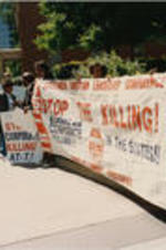 Demonstrators hold a "Stop the Killing" campaign banner at an AT&amp;T protest.