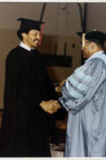 An unidentified graduate shakes hands with Dr. Grant Shockley after receiving his diploma.