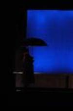 Silhouette view of actors with umbrella on stage.