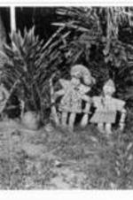 Three small African statues stand in the brush.