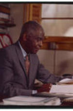 Benjamin E. Mays sits behind his desk in his office.