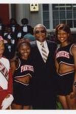 Walter Broadnax poses with two members of the marching band and two cheerleaders at convocation.