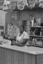 An unidentified woman sits behind the sales counter in a liquor store.