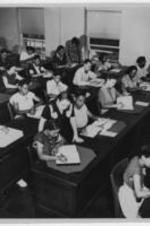 Students receive instruction in a classroom setting. Written on verso: Supervised study in the Atlanta University School of Library Service. Standing near front of picture is Dr. Virginia Lacy Jones, Director of the School. Also standing [are?] two instructors, Miss Lillie K. Daly and Mrs. Hallie B. Brooks.